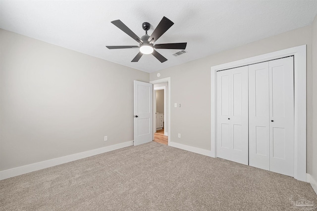 unfurnished bedroom featuring light colored carpet, ceiling fan, and a closet