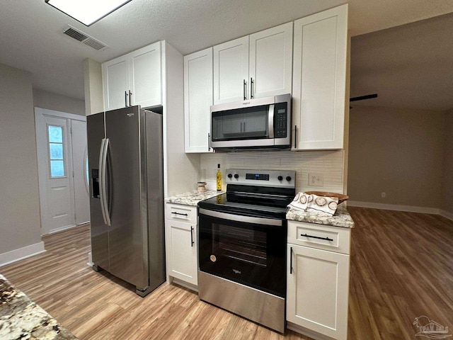 kitchen featuring light stone counters, light hardwood / wood-style floors, white cabinets, and appliances with stainless steel finishes