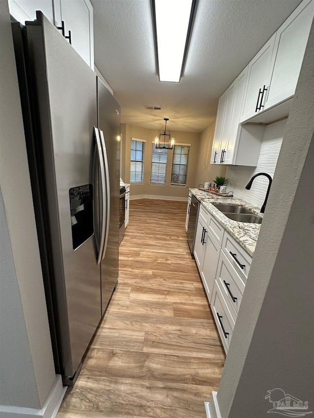 kitchen with white cabinetry, appliances with stainless steel finishes, sink, and light stone counters