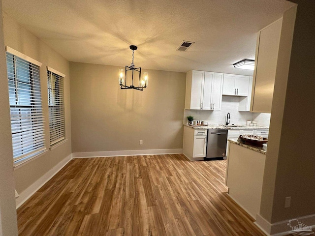 kitchen featuring white cabinetry, hanging light fixtures, light hardwood / wood-style flooring, and stainless steel dishwasher