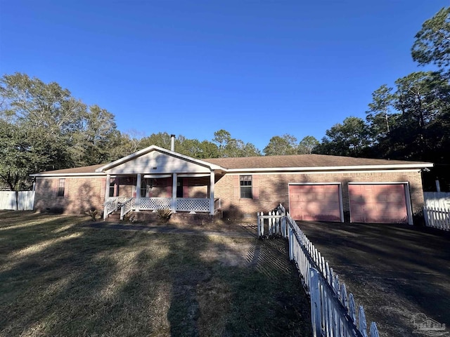 view of front facade featuring aphalt driveway, an attached garage, covered porch, fence, and a front yard