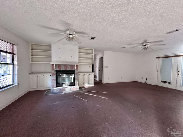 unfurnished living room featuring a glass covered fireplace, visible vents, and ceiling fan