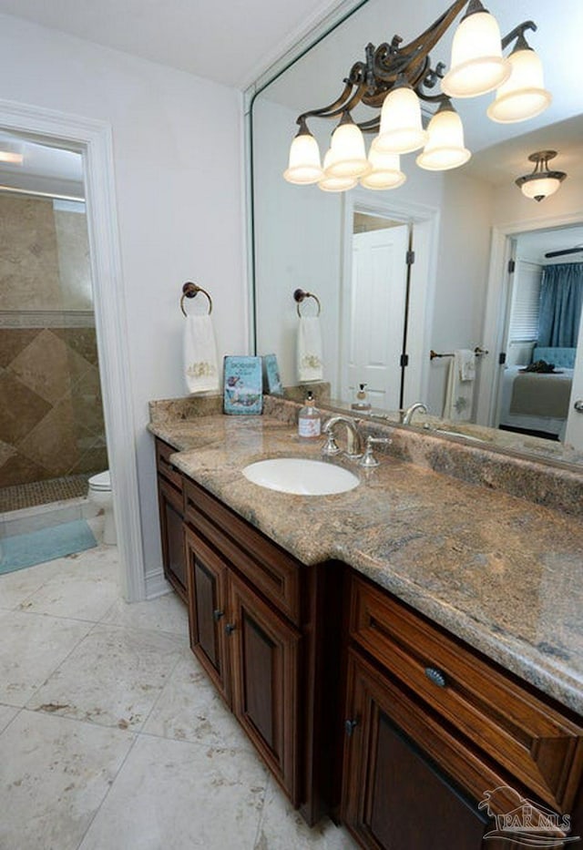 bathroom featuring a tile shower, vanity, and toilet