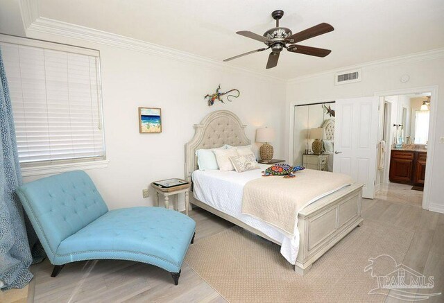 bedroom featuring light wood-style flooring, crown molding, a ceiling fan, and ensuite bath