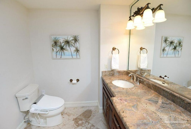 bathroom with toilet, vanity, and baseboards