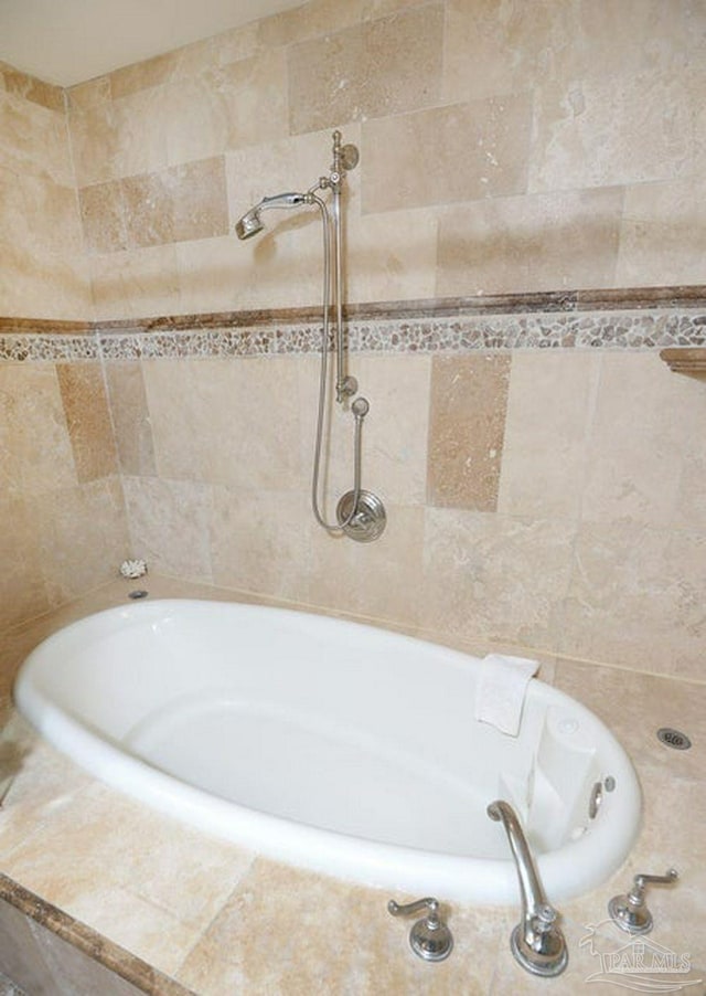 bathroom with a tub and tile walls