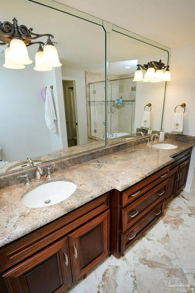 bathroom featuring a stall shower, double vanity, and marble finish floors
