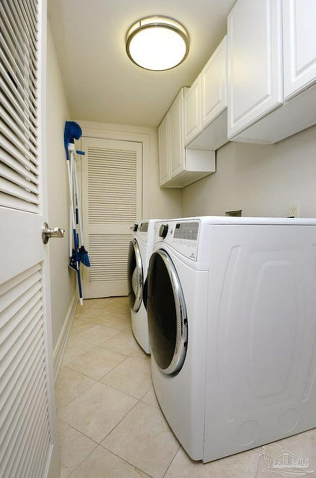 laundry area with cabinet space, washer and dryer, light tile patterned floors, and baseboards