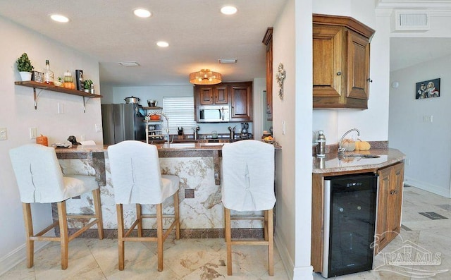 kitchen featuring appliances with stainless steel finishes, wine cooler, a sink, a peninsula, and recessed lighting