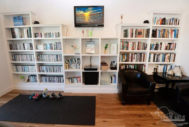sitting room featuring wood finished floors and wall of books