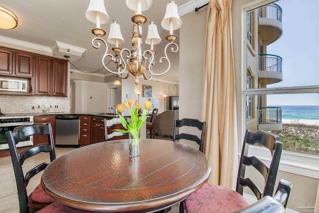 dining area featuring a notable chandelier, sink, ornamental molding, and a water view