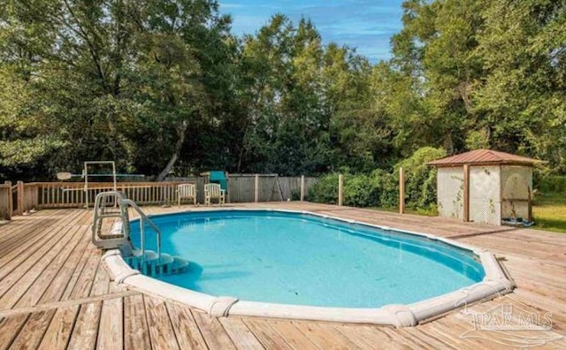 view of swimming pool featuring a deck and a shed