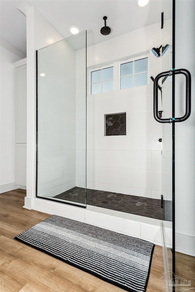 bathroom with wood-type flooring and a shower with shower door