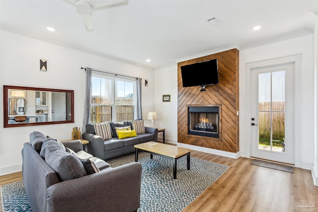 living room with ceiling fan, light hardwood / wood-style floors, ornamental molding, and a fireplace