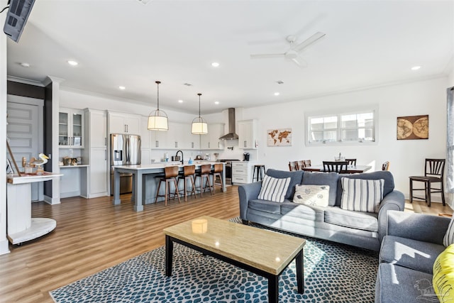 living room featuring ceiling fan, crown molding, and light wood-type flooring