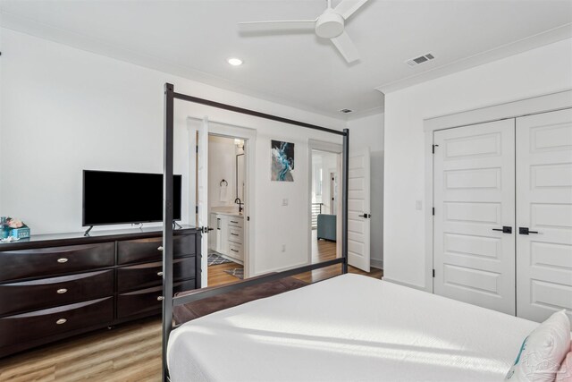 bedroom with ensuite bathroom, ceiling fan, sink, light hardwood / wood-style floors, and a closet