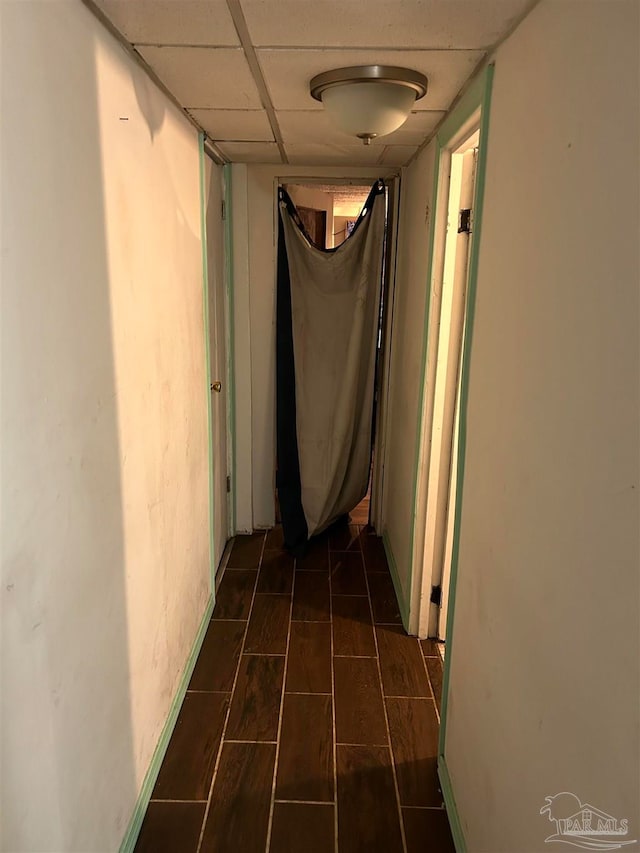 hall with a drop ceiling and dark wood-type flooring