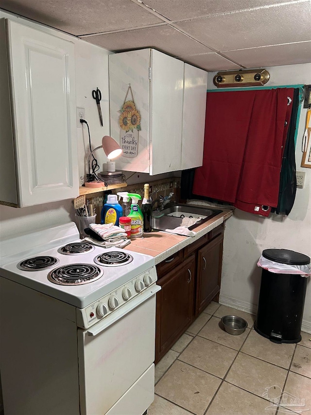 kitchen with dark brown cabinetry, white electric range oven, light tile patterned flooring, sink, and white cabinetry