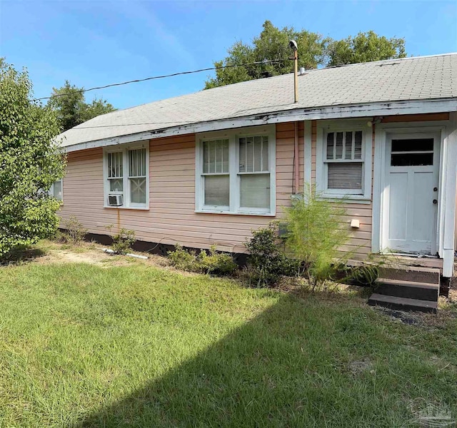 ranch-style house with cooling unit and a front lawn