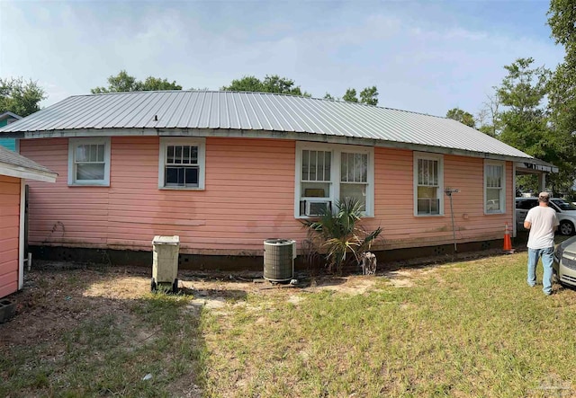 view of side of property featuring central AC unit and a yard