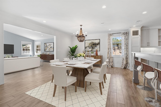 dining area with a chandelier, vaulted ceiling, and light hardwood / wood-style floors