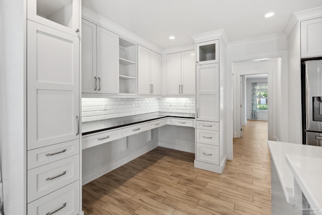 unfurnished office featuring light wood-type flooring and crown molding