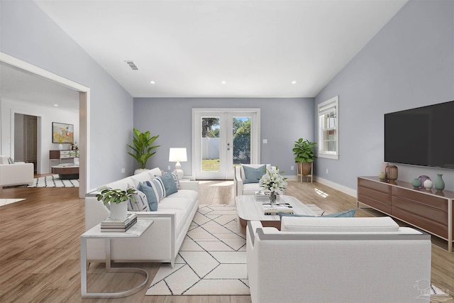 living room featuring french doors, light hardwood / wood-style floors, and vaulted ceiling