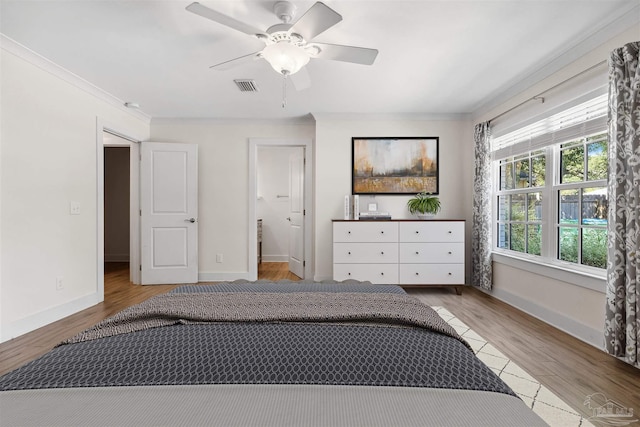 bedroom featuring crown molding, connected bathroom, light hardwood / wood-style flooring, and ceiling fan