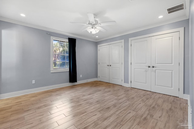 103 Florida Ave, Gulf Breeze, FL 32561 - unfurnished bedroom featuring ornamental molding, multiple closets, visible vents, and light wood-style flooring