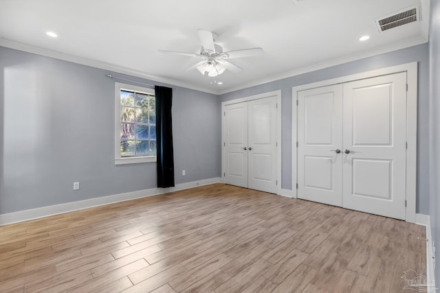 unfurnished bedroom with ornamental molding, ceiling fan, two closets, and light hardwood / wood-style flooring