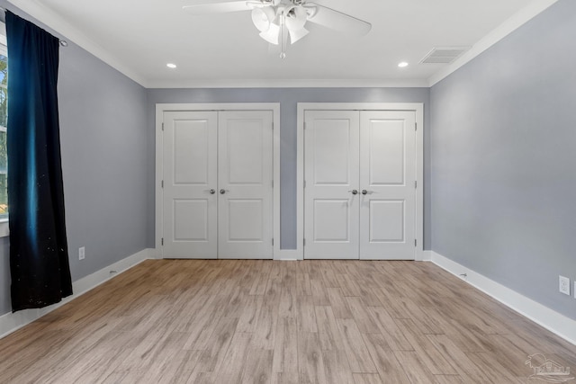 unfurnished bedroom with multiple closets, crown molding, light hardwood / wood-style flooring, and ceiling fan