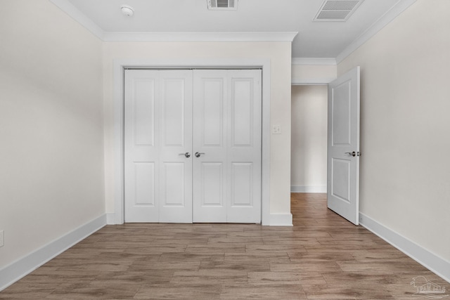 unfurnished bedroom featuring ornamental molding, a closet, and light hardwood / wood-style floors