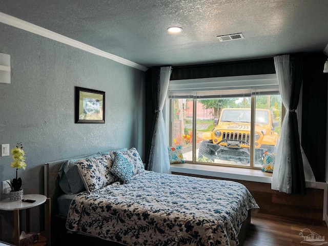 bedroom with a textured ceiling, dark wood-type flooring, and ornamental molding