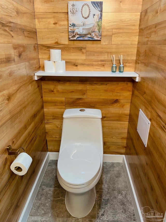 bathroom with toilet, wooden walls, and tile patterned floors