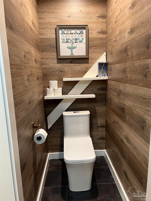 bathroom with tile patterned floors, wooden walls, and toilet