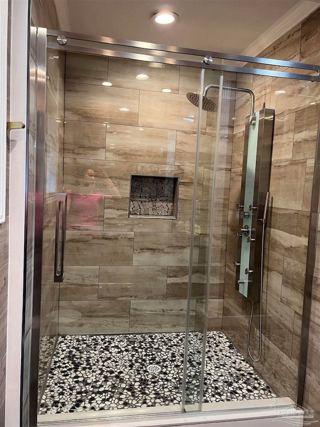 bathroom with ornamental molding and a shower with shower door