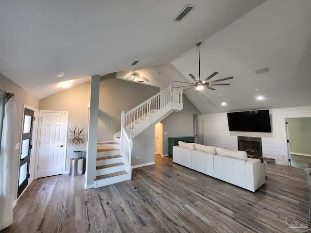 unfurnished living room featuring hardwood / wood-style floors, a large fireplace, vaulted ceiling, and ceiling fan