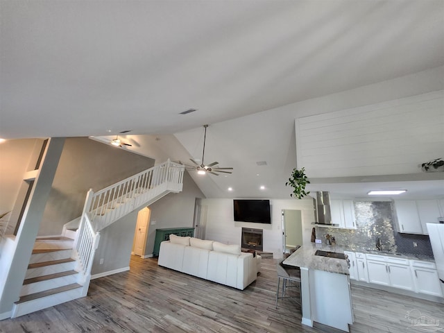 unfurnished living room with light wood-type flooring, vaulted ceiling, and ceiling fan