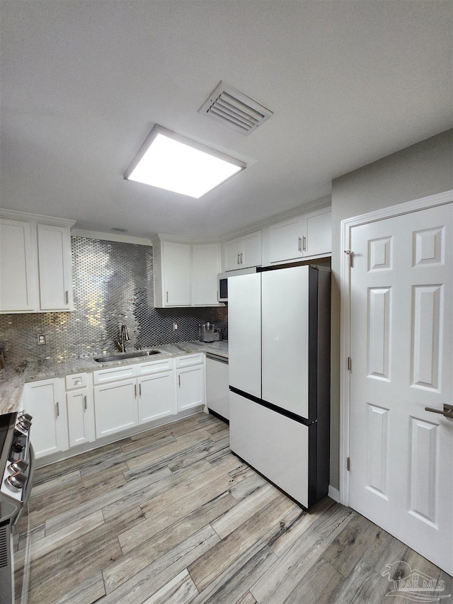 kitchen with white cabinetry, sink, backsplash, light hardwood / wood-style floors, and white appliances