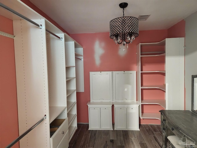 spacious closet with a notable chandelier and dark hardwood / wood-style flooring