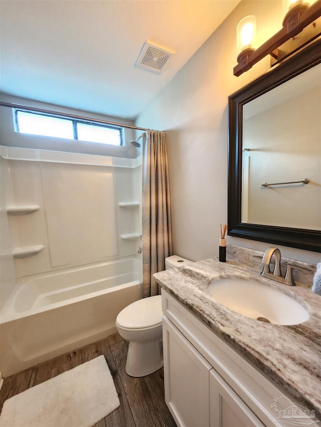 full bathroom featuring hardwood / wood-style floors, vanity, shower / tub combo, and toilet