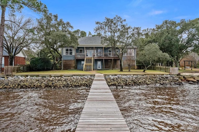 view of dock with a water view and a lawn