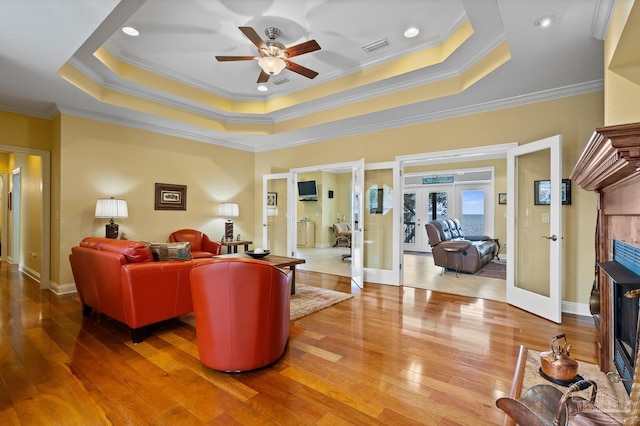 living room with ornamental molding, french doors, and a tray ceiling