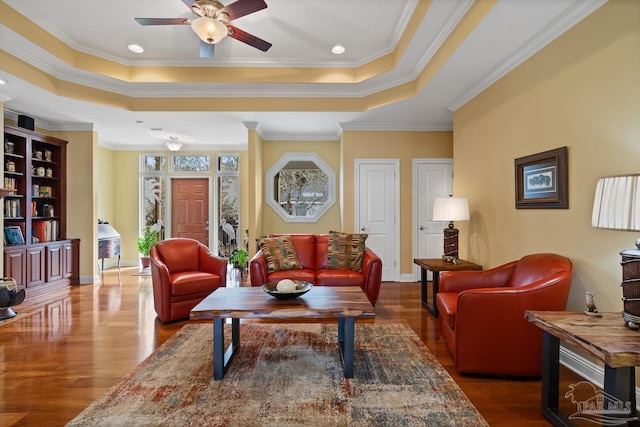 living room featuring crown molding, ceiling fan, dark wood-type flooring, and a tray ceiling