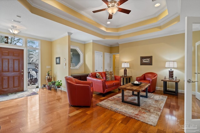 living room with ceiling fan, crown molding, hardwood / wood-style floors, and a tray ceiling