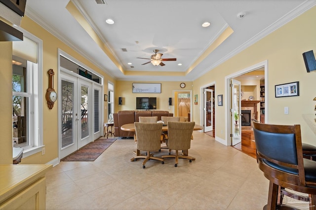 tiled dining room featuring a raised ceiling, a healthy amount of sunlight, french doors, and ceiling fan