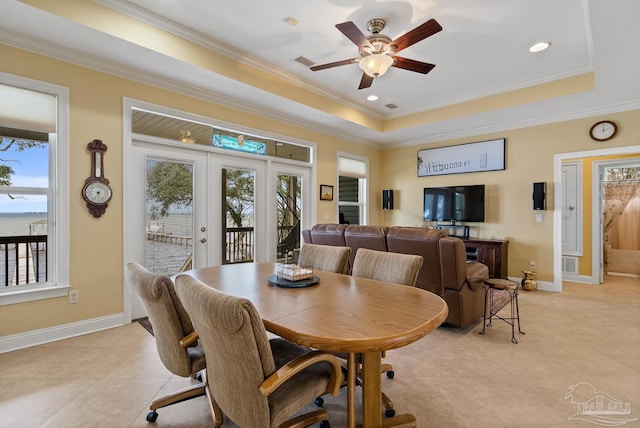 dining space with a raised ceiling, french doors, ornamental molding, and ceiling fan