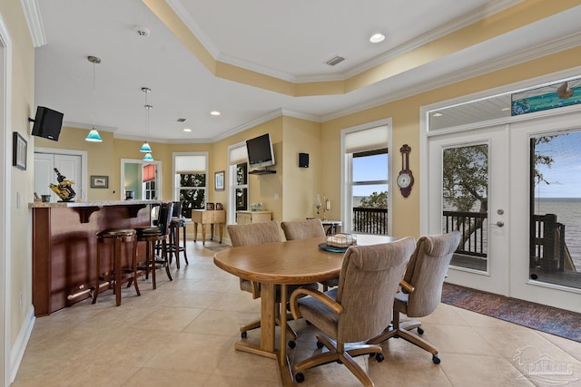 tiled dining space featuring a raised ceiling, french doors, bar area, and crown molding