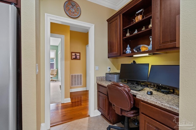 office area with built in desk, crown molding, and light hardwood / wood-style flooring