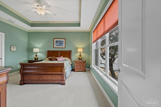 carpeted bedroom with ceiling fan, crown molding, and a tray ceiling